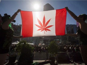 Two people hold a modified design of the Canadian flag with a marijuana leaf in place of the maple leaf during a rally in Toronto in 2016. For the fifth-straight year, the number of cannabis-related offences reported to police in Canada dropped in 2016.