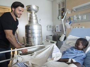 Pittsburgh Penguins' Kris Letang shows off the Stanley Cup to Owen Yekpe during a visit to Ste-Justine Hospital for sick children in Montreal on July 23, 2017.