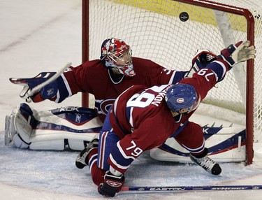Montreal Canadiens defenceman Andrei Markov and goalie Cristobal Huet swat at puck as it flips through the crease in the last minute of Habs pre-season victory over the Ottawa Senators in Montreal September 30, 2006.