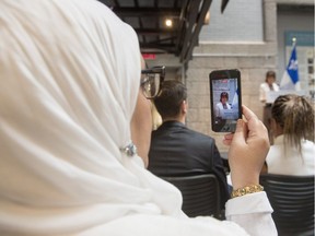 A woman records on her phone as Quebec Immigration, Diversity and Inclusiveness Minister Kathleen Weil makes an announcement about the fight against systemic discrimination and racism on July 20, 2017 in Montreal.