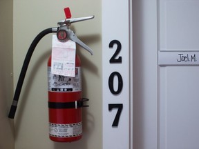A fire extinguisher on a wall near an apartment door.