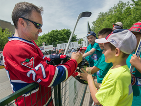 Montreal Canadien's alumni Gilbert Delorme left, signs his autograph as kids line up prior to a Habs legends ball hockey game in Montreal, May  2017.