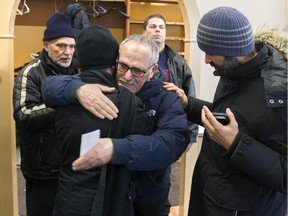 Mohamed Labidi, centre, vice-president of the Centre Culturel Islamique de Québec in Quebec City, is comforted by another man on Feb. 1, 2017, after some people were allowed inside for the first time since a mass shooting at the centre, Jan. 29, in which six people were killed.