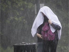 Montreal pedestrian tries to cover up with a towel, during sudden rainstorm to hit at the Camille Houde lookout in Montreal Friday July 21, 2017.
