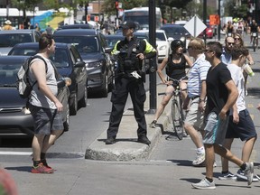 Montreal police officer directs traffic at de Maisonneuve Blvd. and and St-Denis St. on  July 29.