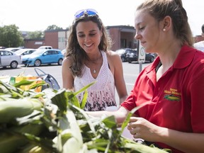 Elizabeth Robitaille, right, serves corn to Genevieve Bruneau at a farm stand outside a mall in Chambly on Aug. 2, 2017.