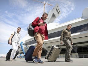 From left, Turkish refugees Cagatay Karaman, Ibrahim Yurtseven and Muhsin Yanik drag their suitcases after leaving the temporary refugee centre at the Olympic Stadium in Montreal on Aug. 7, 2017, after no longer being able to tolerate the living conditions.