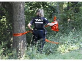 A police officer removes crime scene tape from the scene of a stabbing on Mount Royal on Aug. 8, 2017.