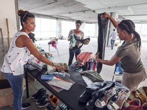 Organizer Cynthia Nelson, left, and volunteers Natasha Kenol and Farah Surpris, right, sort through some of the things that have been donated to help refugees who have arrived in Montreal in the last few weeks, at a donated warehouse space Thursday, Aug. 10, 2017.