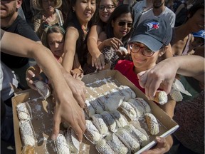 Victoria Scarola on the right, is mobbed by people as they get a free Cannoli at Montreal Italian Week's cannoli contest in Montreal, on Sunday, August 13, 2017.