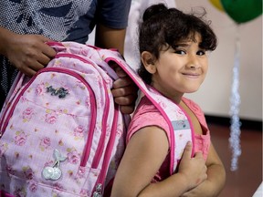 Zara Al-Ameri is all smiles as her brother helps her with a new school bag filled with basic supplies at the Welcome Hall Mission in Montreal on Aug. 15, 2017. Al-Ameri will be entering grade 2.