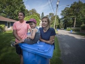 Martin Provost and Simone Clamann with their son in front of their home in Terrasse-Vaudreuil. They were handed a $271 ticket from the town's public security for leaving out a rolling bin the day after the regular pickup day.