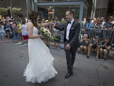 Newlyweds Corey Krakower and Jennifer Smith dance along the parade route and get a large round of applause from attendees of the Pride parade as they head to their hotel for their wedding ceremony  in Montreal, on Sunday, August 20, 2017.