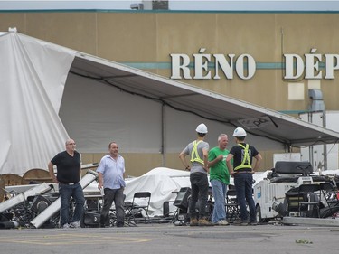 Organizers and workers check out the damage after a severe wind storm ripped apart the large tent that will host partygoers at this year's Strangers in the Night gala at the Fairview Pointe-Claire parking lot on the West Island of Montreal, on Tuesday, August 22, 2017.