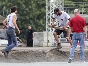 Workers level the dirt in the rodeo ring as they prepare the site for the NomadFest in the Old Port of Montreal.