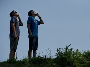 Two boys watch a partial solar eclipse in Dorval on Monday.