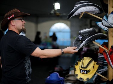 Carl Tremblay of Dos locos, straightens out their cowboy hat display at the rodeo in the Old Port of Montreal, Aug. 24, 2017.