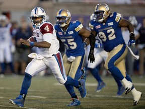 Montreal Alouettes quarterback Darian Durant runs the ball after being pressured by Winnipeg Blue Bombers defensive lineman Jamaal Westerman and Winnipeg Blue Bombers defensive tackle Drake Nevis, right, during CFL action at Molson Stadium in Montreal on Thursday August 24, 2017.