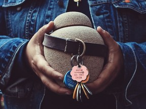 A self-portrait of Paul Labonté holding Marcy's urn with his dog collar and licenses.