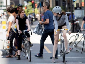 Pedestrians make their way around cyclists who have stopped in the crosswalk in Montreal on Monday August 28, 2017.