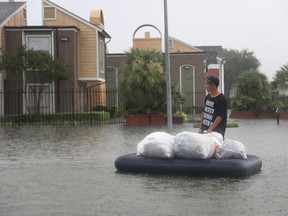 A person uses an air matress to take items down a flooded street as people evacuate their homes after the area was inundated with flooding from Hurricane Harvey on August 27, 2017 in Houston, Texas.