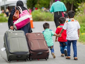 Asylum seekers walk along Roxham Road near Champlain, New York on Aug. 6, 2017, making their way toward the Canada/US border near Hemmingford.