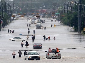 People walk through the flooded waters of Telephone Rd. in Houston on August 27, 2017 as the US fourth city city battles with tropical storm Harvey and resulting floods.