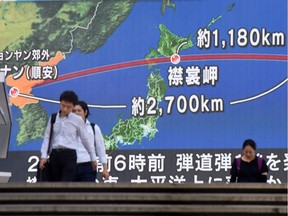 Pedestrians walk in front of a huge screen displaying a map of Japan (R) and the Korean Peninsula, in Tokyo on August 29, 2017, following a North Korean missile test that passed over Japan.  Abe said on August 29 that he and US President Donald Trump agreed to hike pressure on North Korea after it launched a ballistic missile over Japan, in Pyongyang's most serious provocation in years.