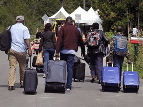 Members of a family from Haiti approach a tent in St-Bernard-de-Lacolle, stationed by Royal Canadian Mounted Police, as they haul their luggage down Roxham Rd. in Champlain, N.Y.