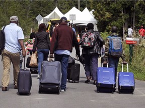 A family of asylum-seekers from Haiti approach the border at St-Bernard-de-Lacolle from Champlain, N.Y., on Aug. 7, 2017.