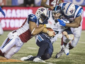 Argonauts quarterback Cody Fajardo, centre, is sandwiched by Alouettes' John Bowman (7) and Kyries Hebert during second half action last week at Molson Stadium.