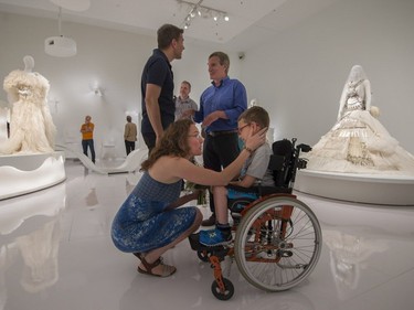 Isabelle Binet-Rochette speaks with her son Erwan as her partner, Manouane Beauchamp, speaks with his uncle behind her, prior to a quick engagement ceremony announcement in the heart of the exhibition, Love Is Love: Wedding Bliss for All a la Jean Paul Gaultier at the Montreal Museum of Fine Arts in Montreal on Saturday, August 12, 2017.