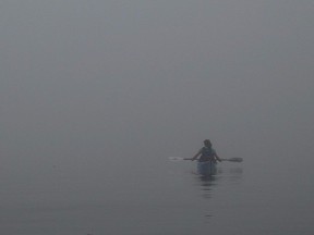 Kayaker listens to a passing lobster boat as she navigates her kayak in the fog, 2008.