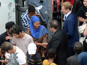 Montreal Mayor Denis Coderre, centre right, greets newly-arrived asylum seekers at a reception area at the Olympic Stadium, in Montreal on Thursday, Aug. 3, 2017.