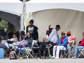 Asylum seekers wait to be transported to a processing centre after entering Canada illegally from the United States at Roxham road in Hemmingford, Que., Wednesday, August 9, 2017.
