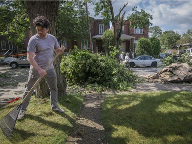 Bruno Fortin cleans up pieces of his neighbour's roof that landed in his front yard in the Montreal borough of Notre-Dame-de-Grace on Wednesday, August 23, 2017. A severe wind storm that ripped through the area Tuesday August 22 caused tremendous damage to trees, cars and rooftops. THE CANADIAN PRESS/Peter McCabe
