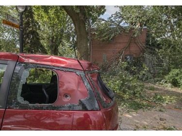 One of many damaged automobiles sits on the side of the road in the Montreal borough of Notre-Dame-de-Grace on Wednesday, August 23, 2017. A severe wind storm that ripped through the area Tuesday August 22 caused tremendous damage to trees, cars and rooftops. THE CANADIAN PRESS/Peter McCabe
