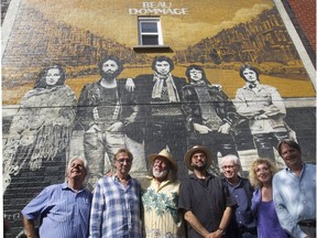 Qubec band Beau Dommage, from the left, Pierre Huet, Michel Hinton, Pierre Bertrand,  Michel Rivard, Robert Léger Marie-Michèle Desrosiers and Réal Desrosiers pose beside an image from one of their albums in an alleyway in the Rosement–La-Petite-Patrie area of Montreal Monday, June 22, 2015.  Beau Dommage was inducted Saturday night in the Canadian Songwriters Hall of Fame.