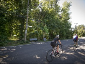 Cyclists pass by a vacant lot on Lakeshore Rd. which Baie-d’Urfé town council voted to approve a purchase offer.