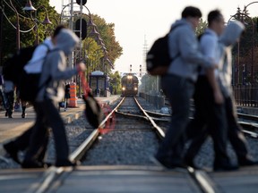 Royal West students walk to school with a train the background, at the Montreal West station in Montreal Sept. 13, 2017.