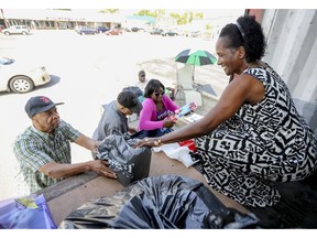 Keith Brown, left, contributes to relief effort set up in LaSalle by the Antigua and Barbuda Association, overseen by Kathleen James, right, Juleen Barrington, second from right, and Kendell Gore.