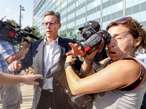 Robert Marcil, former head of Montreal's public works department, shoves Le Devoir photographer Anik de Carufel as he leaves Sureté du Québec headquarters on Tuesday.