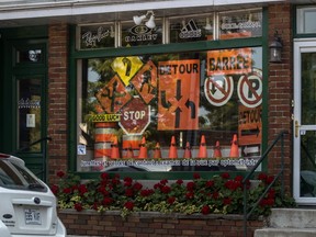 The Dubuc Opticiens store window is decorated with orange traffic cones, “Detour” and “Rue Barrée" signs.