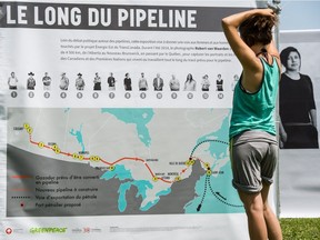 Melissa Lachance of Montreal looks at a map of the proposed Energy East pipeline at a rally organized by Greenpeace and other groups at Jack Layton Park, in Hudson on July 4, 2015. The peaceful gathering of some 150 people, was  to raise public awareness of the environmental consequences of buried pipelines, transporting Alberta tars sands oil through the province to terminals on the St. Lawrence River and St. John, N.B.