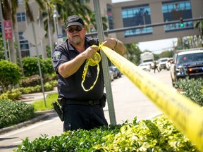 A Hollywood Police Department officer wraps crime scene tape around a perimeter surrounding a rehabilitation centre where eight patients were found dead September 13, 2017 in Hollywood, Florida.