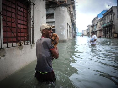 A Cuban and his dog wade through a flooded street in Havana, Sept. 10, 2017. Deadly Hurricane Irma battered central Cuba on Saturday, knocking down power lines, uprooting trees and ripping the roofs off homes as it headed towards Florida. (Yamil Lage, AFP/Getty Images)