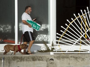 A man carries a street sign that fell during Hurricane Irma in Miami, Florida, Sept. 11, 2017.