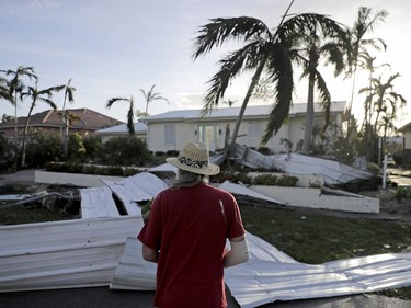 A roof is strewn across a home's lawn as Rick Freedman checks his neighbour's damage from Hurricane Irma in Marco Island, Fla., Sept. 11, 2017. (David Goldman, AP)