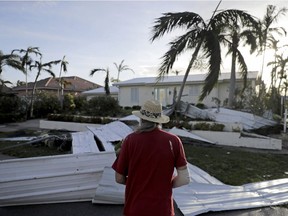 A roof is strewn across a home's lawn as Rick Freedman checks his neighbour's damage after Hurricane Irma in Marco Island, Fla., Sept. 11, 2017.