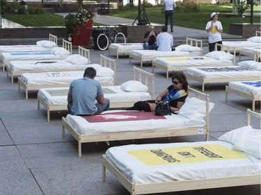 People lie on beds on an outdoor esplanade as a representation of the famous 1969 bed-in by John Lennon and Yoko Ono on the International Day of Peace Thursday, September 21, 2017 in Montreal. THE CANADIAN PRESS/Paul Chiasson
